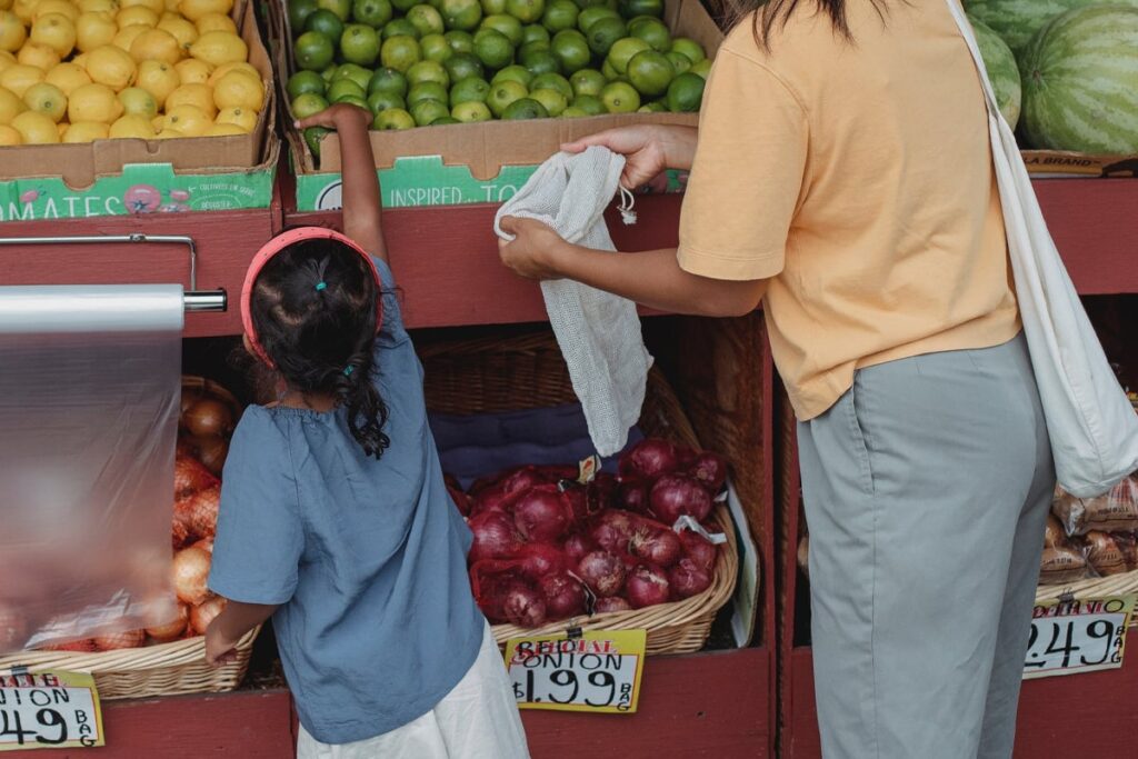 Mother and daughter buying fruits with their eco bag